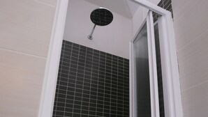 A shower area with a white door, black tiled walls, and a visible showerhead. - Rooms Monteverde (Rome)