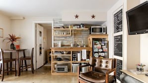 Una cocina compacta con cubierta de madera, un microondas y un menú en una pizarra.
