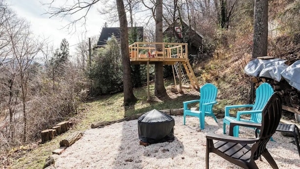 Una terraza de madera con una casita de juegos, mobiliario exterior y una chimenea cubierta.