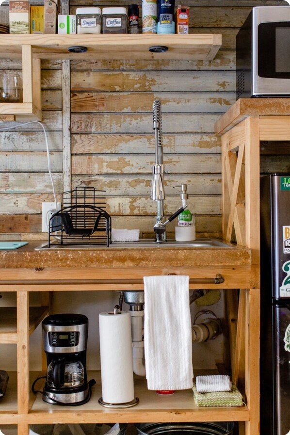 Una cocina con encimera de madera, cafetera, hervidor y microondas.