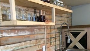Una cocina rústica con estantes de madera, un lavamanos de acero inoxidable y una encimera de madera.