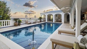 A poolside area with lounge chairs, a pool, and a view of the sea. - NEW LISTING: Hidden Pearl Luxurious Villa - Ocean View (Philipsburg)