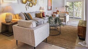A spacious living room with a high ceiling, a wooden ceiling fan, a sofa, a coffee table, and a large window providing natural light. - NEW LISTING: Hidden Pearl Luxurious Villa - Ocean View (Philipsburg)