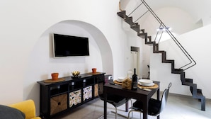 A modern living room with a black dining table, yellow sofa, and a black staircase with a unique design.