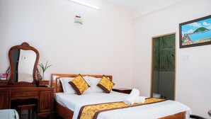 A neatly arranged hotel room with a wooden bed, a desk, and a mirror.