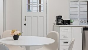 A modern kitchen with white cabinetry, a round dining table, and four chairs. - Walkerville 1BR Suite Near Caesars Windsor | RiverWalk, Waterfront & Downtown (Windsor)