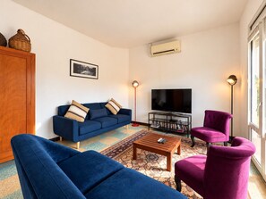 Una sala de estar con sofá, sillones, una mesa de centro, televisor y estantería.