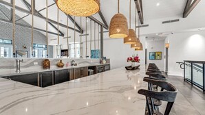 A modern kitchen with a large island, pendant lights, and a bar area with stools.