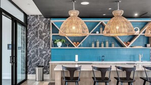 A modern kitchen with a blue backsplash, black and white patterned wall, and three hanging wicker pendant lights.