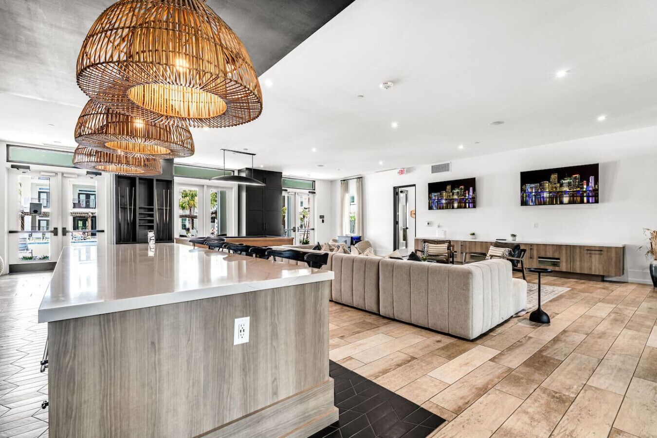 Een moderne keuken met een centraal eiland, een zithoek met een bank en een grote hanglamp.