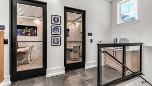 A modern interior with two glass doors leading to a dining area, a staircase, and a kitchen area. - Tropical Hideaway: Amazing 3-Bed Oasis with Pool (Apollo Beach)