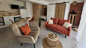 A modern living room with a sofa, armchair, and a dining area with a table and chairs. - Cocon d'Amour & Spa (Le Thoronet)