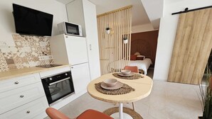 A modern kitchen with white cabinets, a microwave, and a TV mounted above the counter. - Cocon d'Amour & Spa (Le Thoronet)