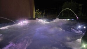 A hot tub with water jets and lights, surrounded by a building and trees. - Cocon d'Amour & Spa (Le Thoronet)