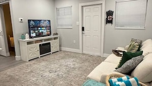 Una sala de estar moderna con un televisor de pantalla plana, un sofá blanco y un baúl color turquesa como mesa de centro.