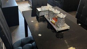 A modern living room with a black sofa, a black armchair, and a dining table with a decorative centerpiece. - Charming 2-bedroom flat in superb London with WiFi, AC, toiletries, quite area (London)