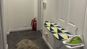 A hallway with a fur rug, a fire extinguisher, and an ironing board with an iron. - Charming 2-bedroom flat in superb London with WiFi, AC, toiletries, quite area (London)