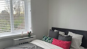 A neatly made bed with a grey and white duvet, a grey headboard, and multiple pillows in various colors. - Charming 2-bedroom flat in superb London with WiFi, AC, toiletries, quite area (London)