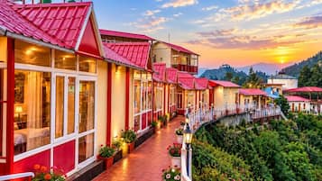 A hotel with a red roof, a covered walkway, and a view of the mountains.
