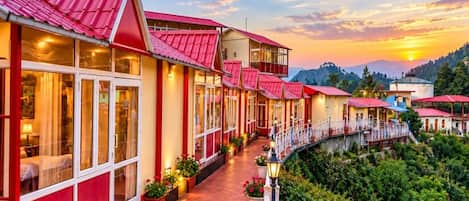 A hotel with a red roof, a covered walkway, and a view of the mountains.