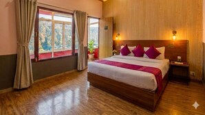 A hotel room with a wooden ceiling, a large bed with a headboard, a nightstand, and a window with curtains. - AUREVELLE KASTURA RESORT KANATAL (Kanatal)