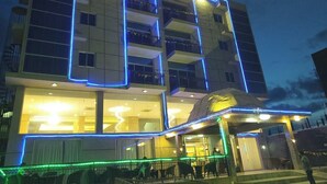 A hotel with a modern facade, balconies, and illuminated signage.