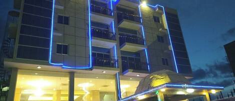 Un hotel con fachada moderna, balcones e iluminación de señalización.