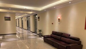 A hotel lobby with a marble floor, a leather sofa, and a reception desk.