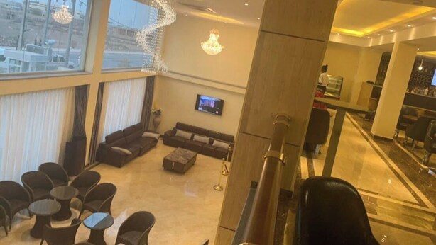 A spacious lounge area with a large window, a sofa, and multiple chairs.