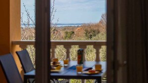 A balcony with a table set for breakfast, overlooking a landscape with trees and a distant view.