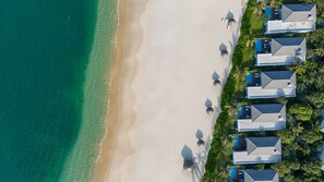 An aerial view of a beachfront resort with multiple bungalow-style buildings, a sandy beach, and clear turquoise waters. - Luxury Marriot Resort & Spa - Nha Trang (Nha Trang)