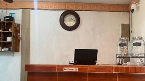 A reception desk with a clock, a laptop, and a sign that reads "No Fumar". - Casa 12 Reales (Guanajuato)