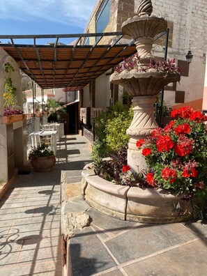 A courtyard with a stone fountain, potted plants, and outdoor seating. - Casa 12 Reales (Guanajuato)