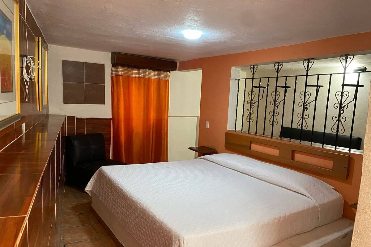 A hotel room with a bed, a desk, and a chair.