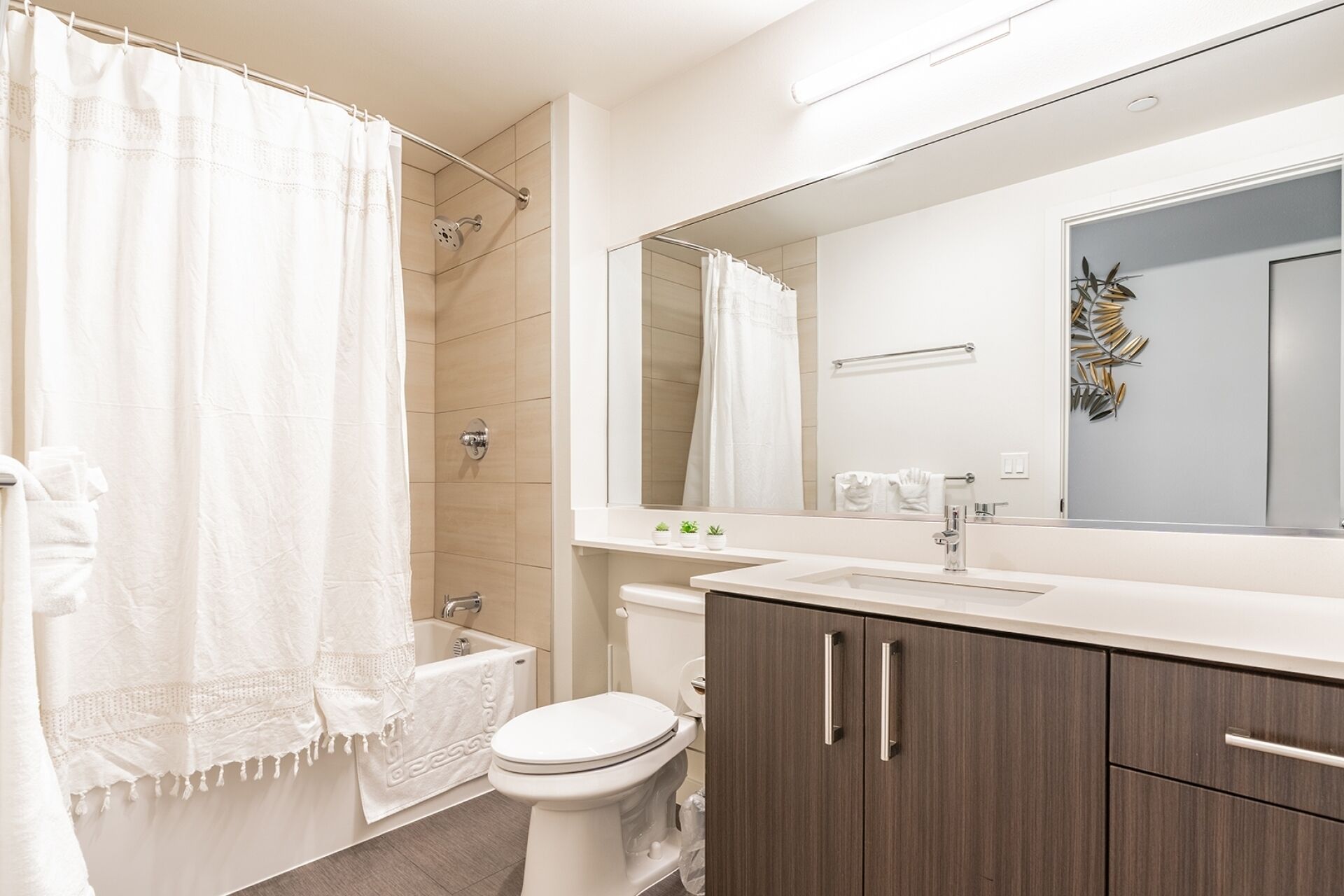 A bathroom with a shower, toilet, sink, and vanity.