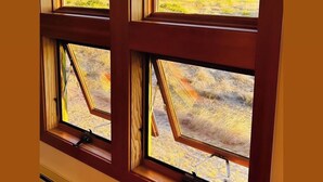 Ein Zimmer mit mehreren Fenstern und Blick auf eine gebirgige Landschaft.