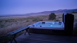 Ein Whirlpool auf einer Holzterrasse mit Blick auf eine natürliche Landschaft.