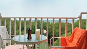 Un balcon avec une table en verre, une bougie et une bouteille.