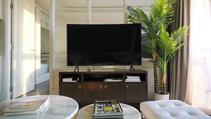 Un salon moderne avec un téléviseur à écran plat, une plante en pot et un canapé.