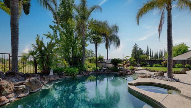 A swimming pool surrounded by tropical plants and palm trees. - Spacious 5-bedroom tropical paradise resort style pool spa scenic sunset views (Roseville)
