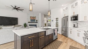 A modern kitchen with dark cabinets, a large island, stainless steel appliances, and pendant lighting. - Spacious 5-bedroom tropical paradise resort style pool spa scenic sunset views (Roseville)