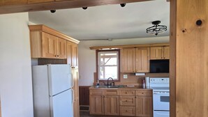 Una cocina con armarios de madera, un refrigerador, un lavamanos y una estufa.