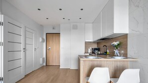 Une cuisine moderne avec un îlot central en bois, des chaises blanches et une porte en bois.