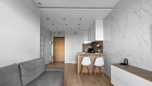 Une cuisine moderne avec un pare-feu en marbre, un plan de travail en bois et deux chaises blanches.