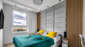 Une chambre moderne avec un grand lit, une table de chevet, une fenêtre donnant sur un beau paysage et un mur revêtu de panneaux en bois.