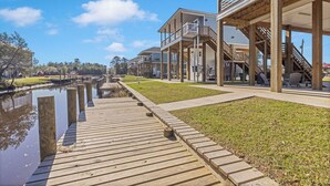 A wooden deck leading to a waterfront property with multiple levels and balconies. - Waterfront Escape in Bay STL with dock,pickleball, ping pong, basketball & more! (Bay St. Louis)