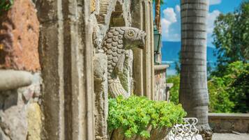 Escultura de piedra con forma de pez, con un macetero de plantas verdes, parte del exterior de un edificio.