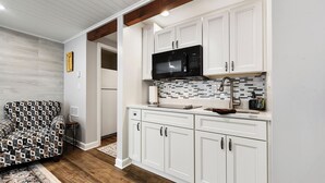 Una cocina moderna con armarios blancos, un microondas negro y un salpicadero de azulejos.