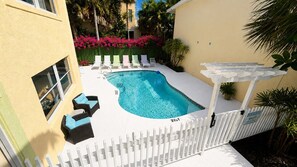 A swimming pool with lounge chairs and a white fence. - Penguins on the Beach | 2BR Steps to Beach & Downtown w/pool | Unit A (Cocoa Beach)