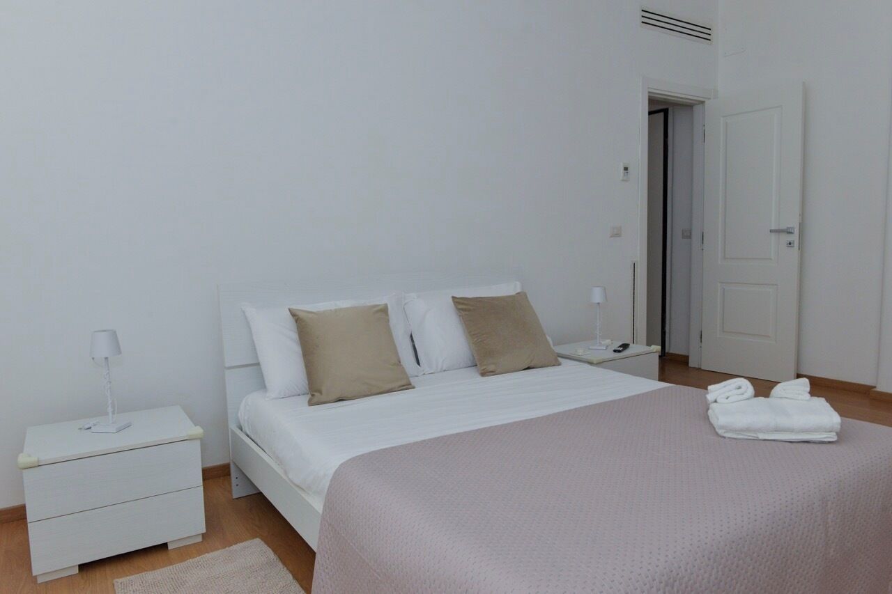 A minimalist bedroom with a bed, nightstands, and a door.